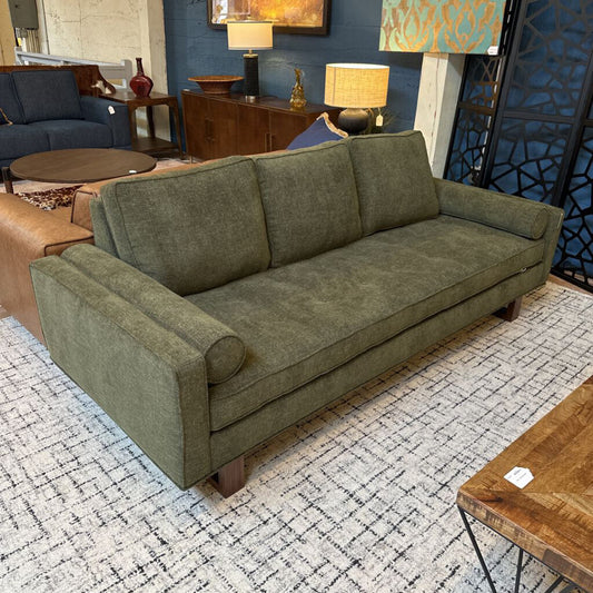 Green sofa in a room with decorative elements and furniture.