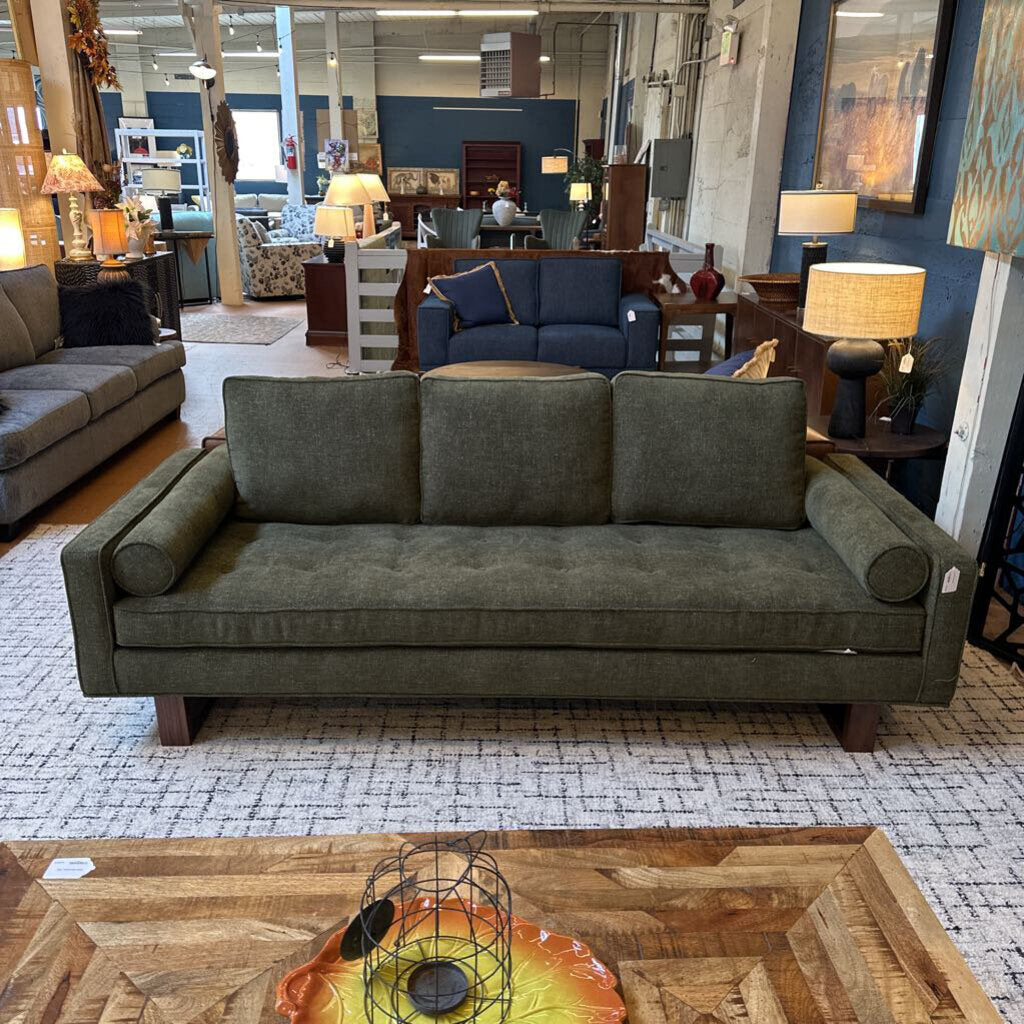 Gray sofa in a furniture store with a wooden coffee table and various decor items.