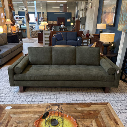 Gray sofa in a furniture store with a wooden coffee table and various decor items.
