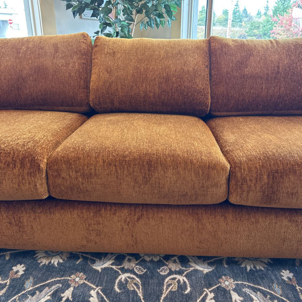 Brown sofa in a room with a window and plant in the background