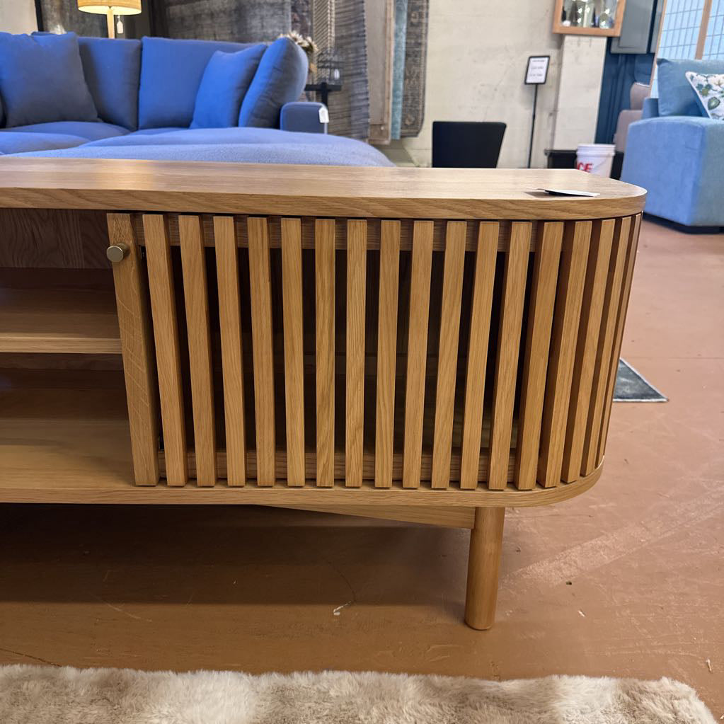 Wooden sideboard in a room with blue sofas and a rug.