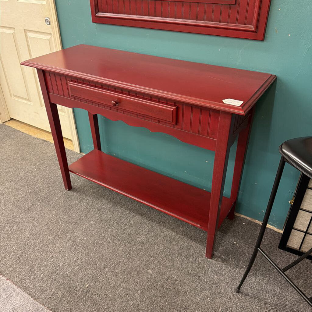 Red console table against a teal wall with a door in the background
