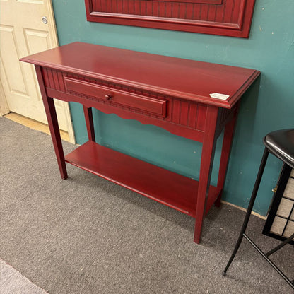Red console table against a teal wall with a door in the background