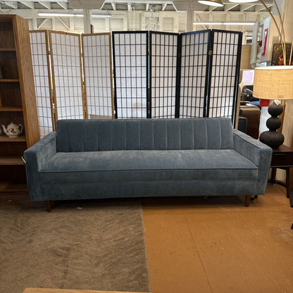 Blue sofa in a room with a folding screen and bookshelf.