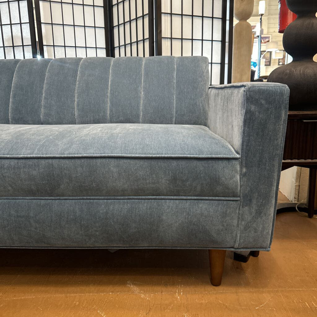 Gray sofa in a room with wooden flooring and a window in the background
