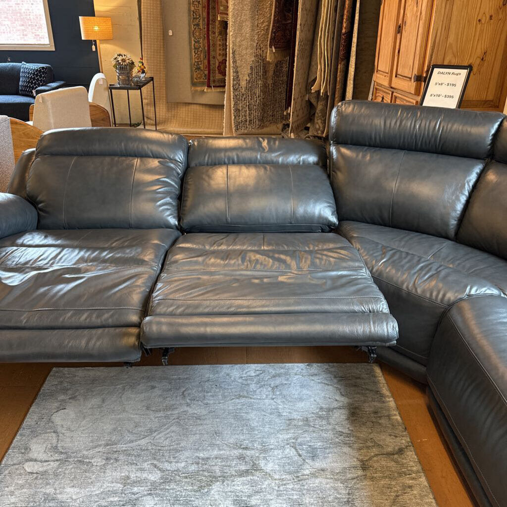 Gray leather sectional sofa in a living room setting with a rug and furniture.