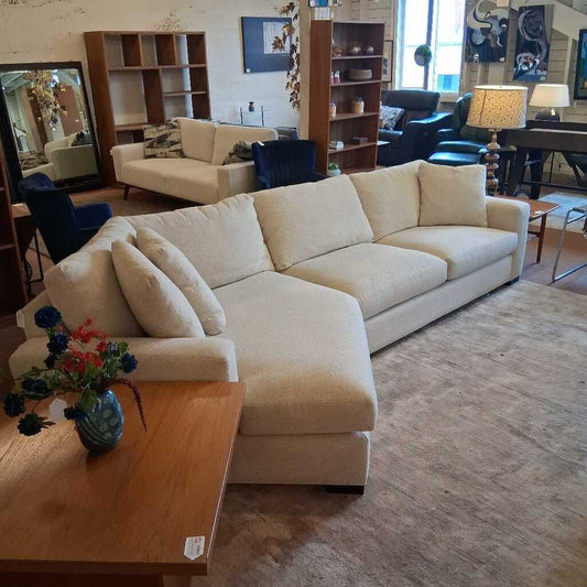 Beige sectional sofa in a living room setting with a coffee table and decorative items.
