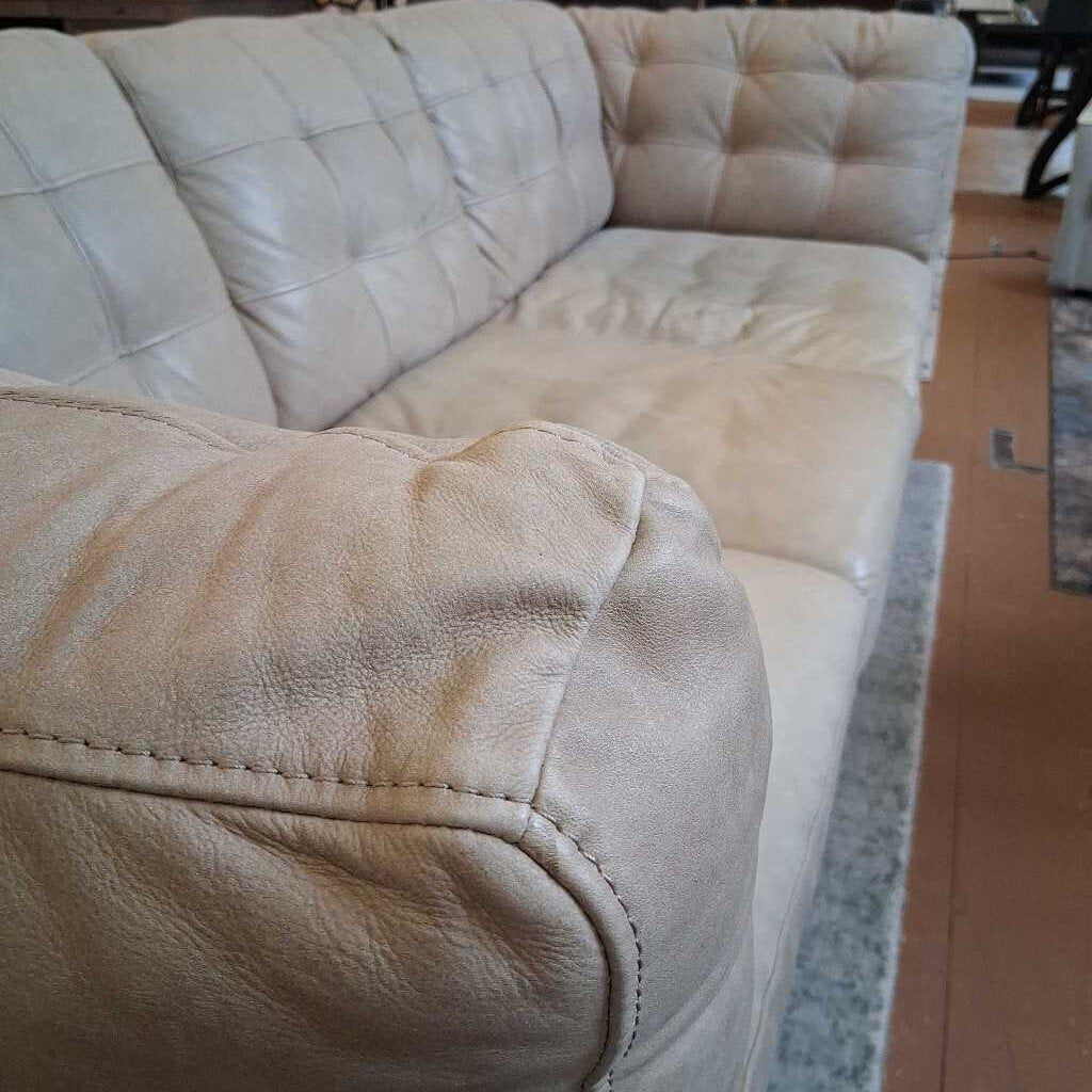 Beige sectional sofa with visible wear and tear in a room setting.