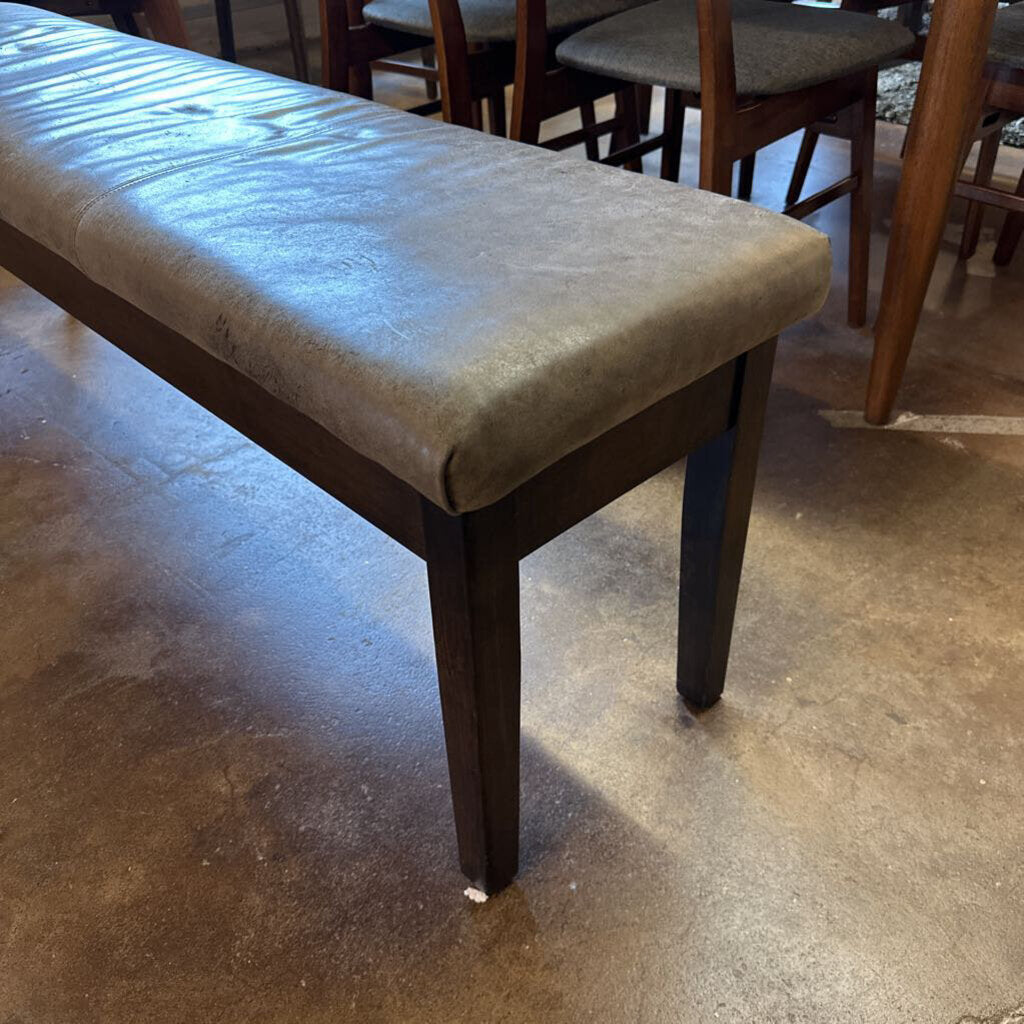 Wooden bench with a cushioned seat on a concrete floor