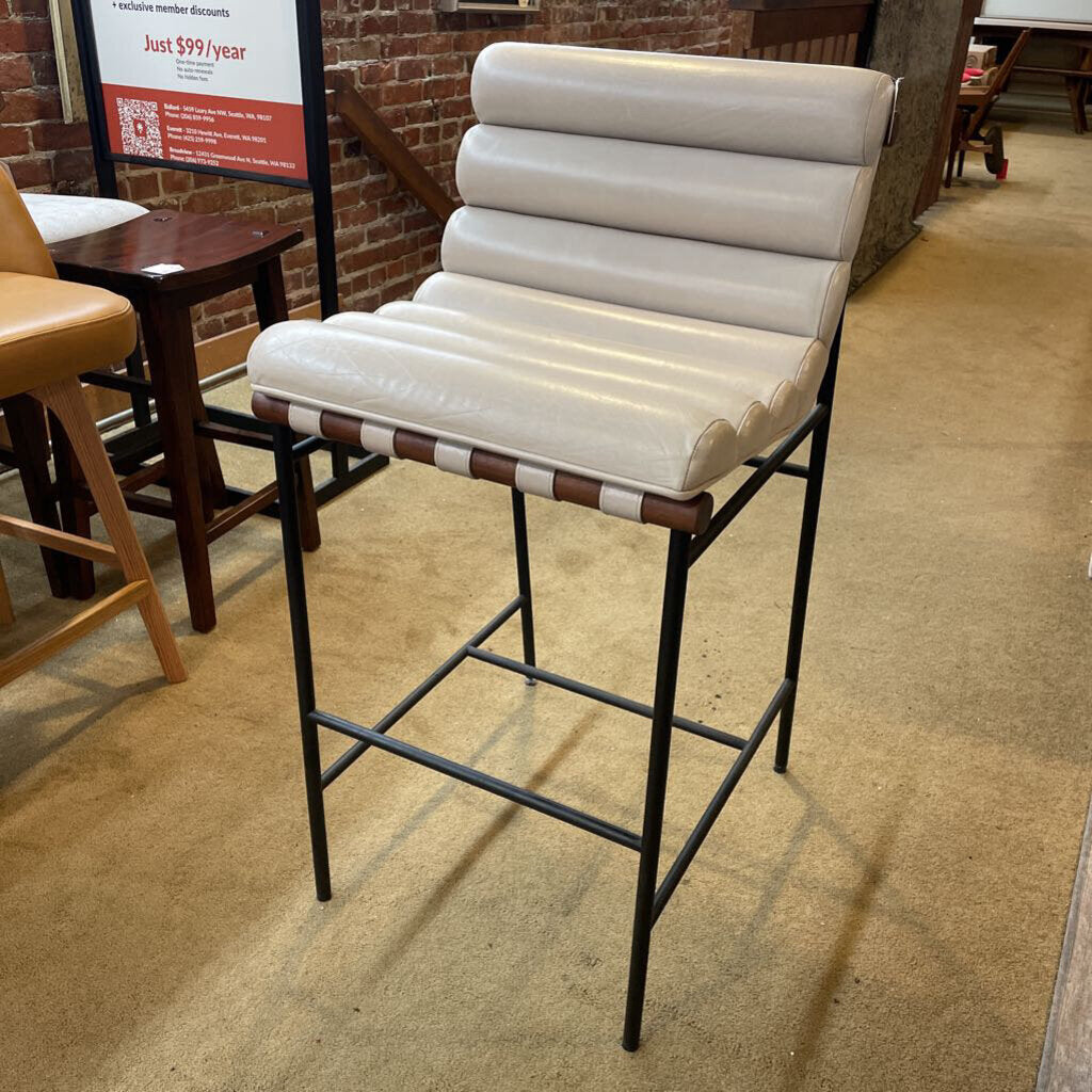 Bar stool with white cushioned seat and backrest in a casual dining setting.