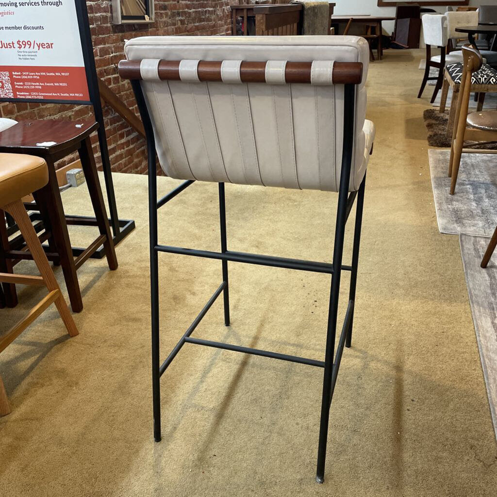 Bar stool with white cushioned seat and brown backrest in a store setting.