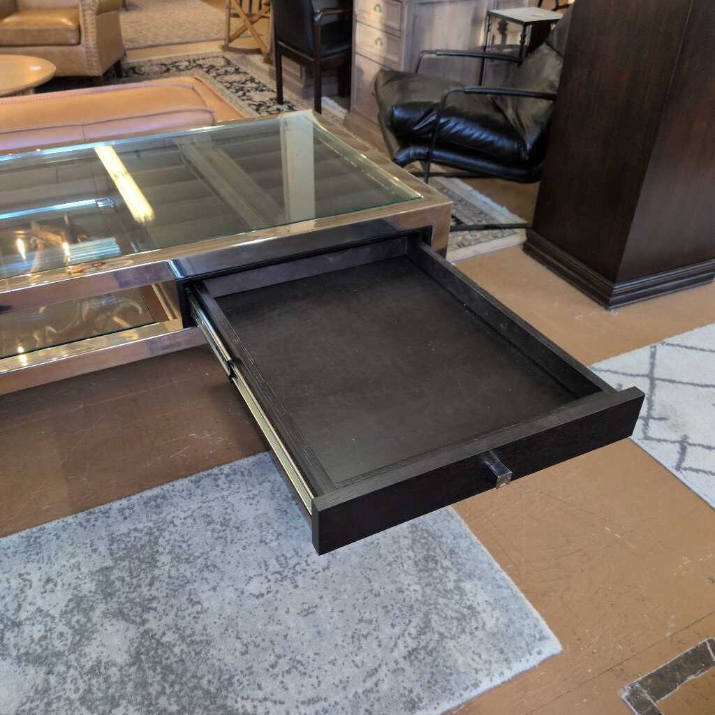 Glass-top coffee table with an open drawer in a living room setting
