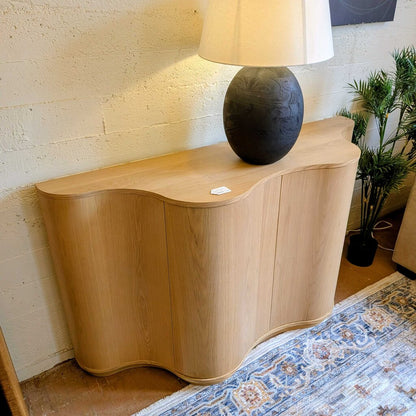 Wooden side table with a lamp on top against a textured wall.
