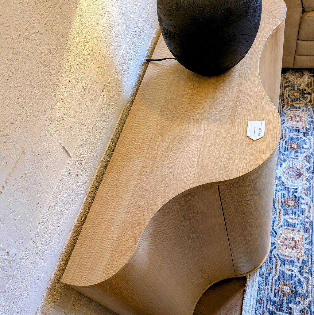 Wooden side table with a decorative item on a textured floor