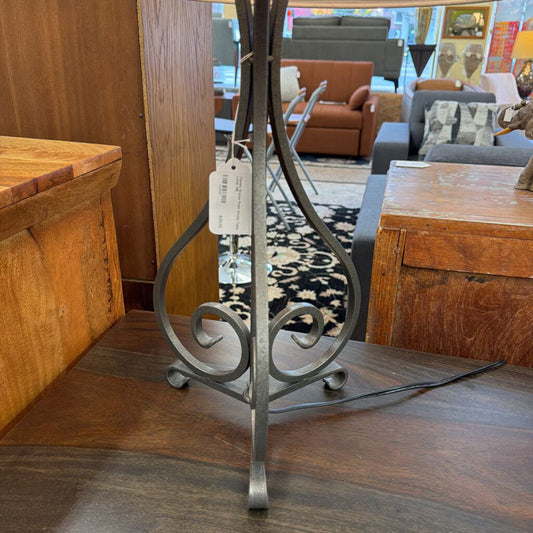 Decorative metal stand on a wooden surface with furniture in the background