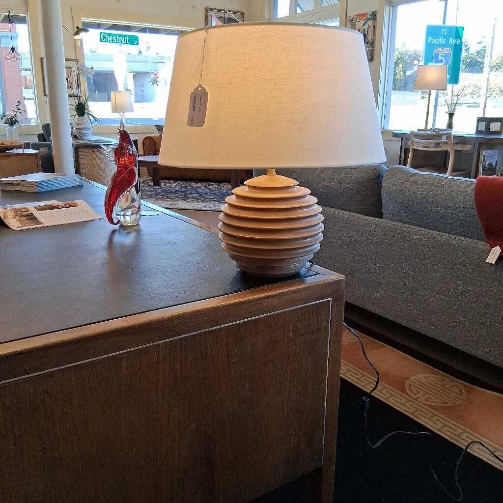 Wooden lamp on a table in a room with a couch and decorative items.