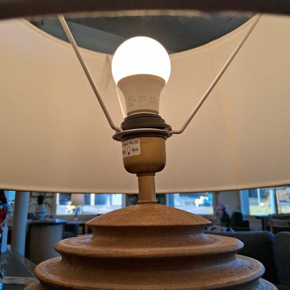 Light bulb inside a lamp with a beige shade in an indoor setting