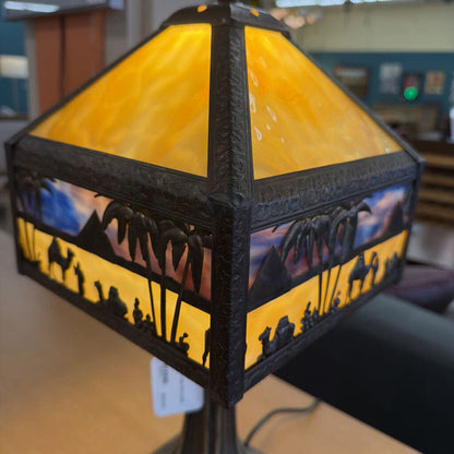 Decorative lamp with stained glass design featuring people and landscape.