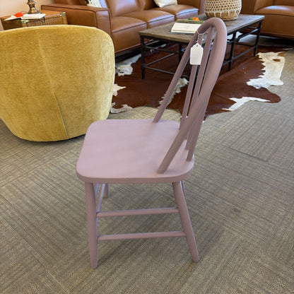 Pink chair on a carpeted floor with a yellow armchair and brown furniture in the background.