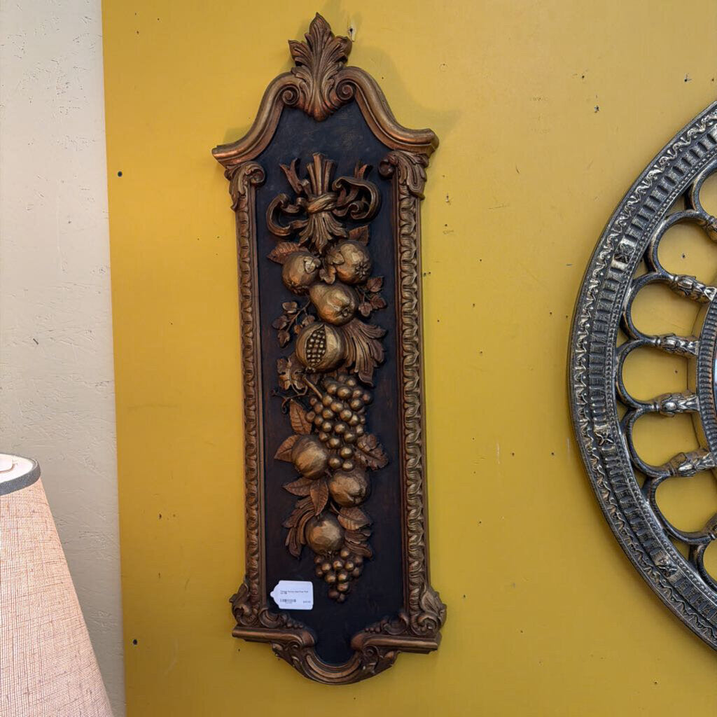 Decorative wall plaque with intricate designs on a yellow wall