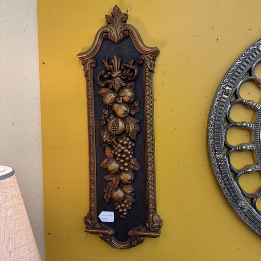 Decorative wall plaque with intricate designs on a yellow wall