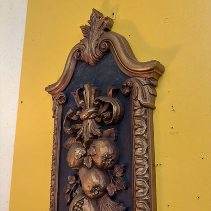 Decorative wooden panel with intricate carvings on a yellow wall.