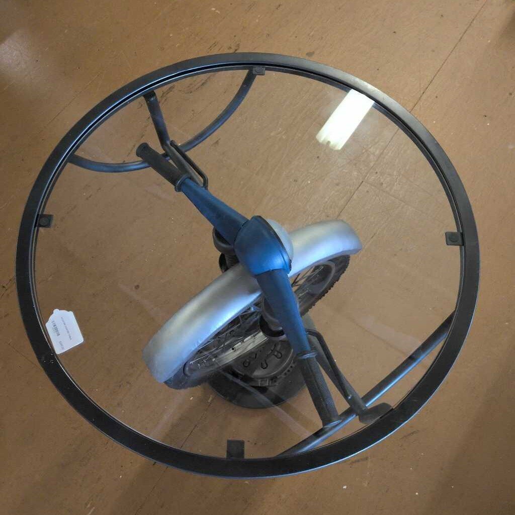 Glass table with metal frame and wheels on a wooden floor