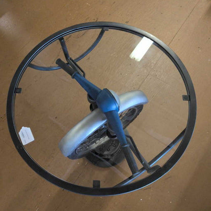 Glass table with metal frame and wheels on a wooden floor