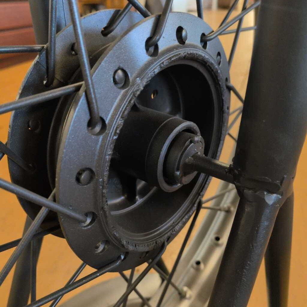 Close-up of a bicycle hub with spokes and a wooden floor background