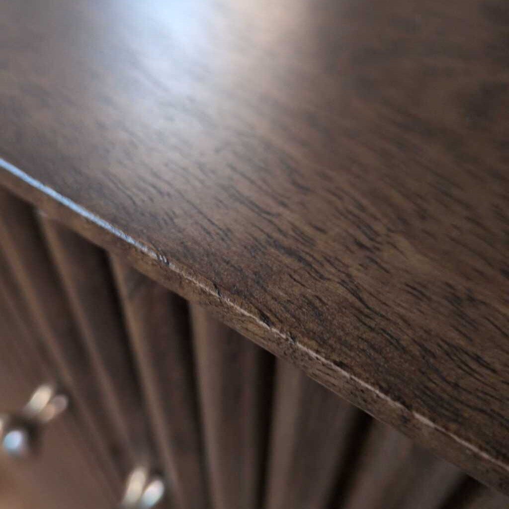 Wooden cabinet with ribbed texture and two doors in a room setting.