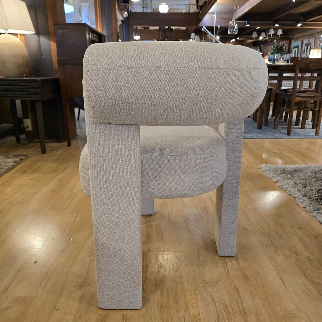 Gray upholstered chair on a wooden floor in a showroom setting