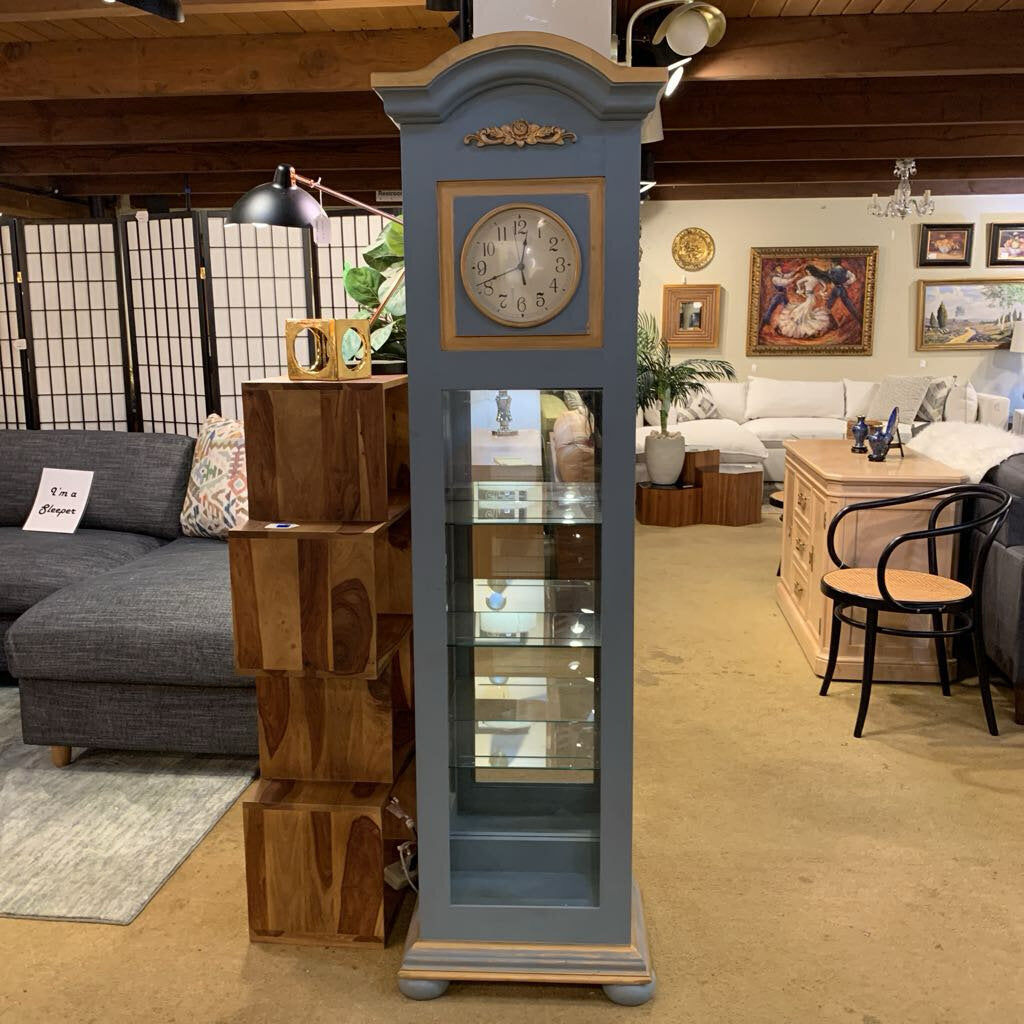 Gray grandfather clock in a living room setting with furniture and decor.
