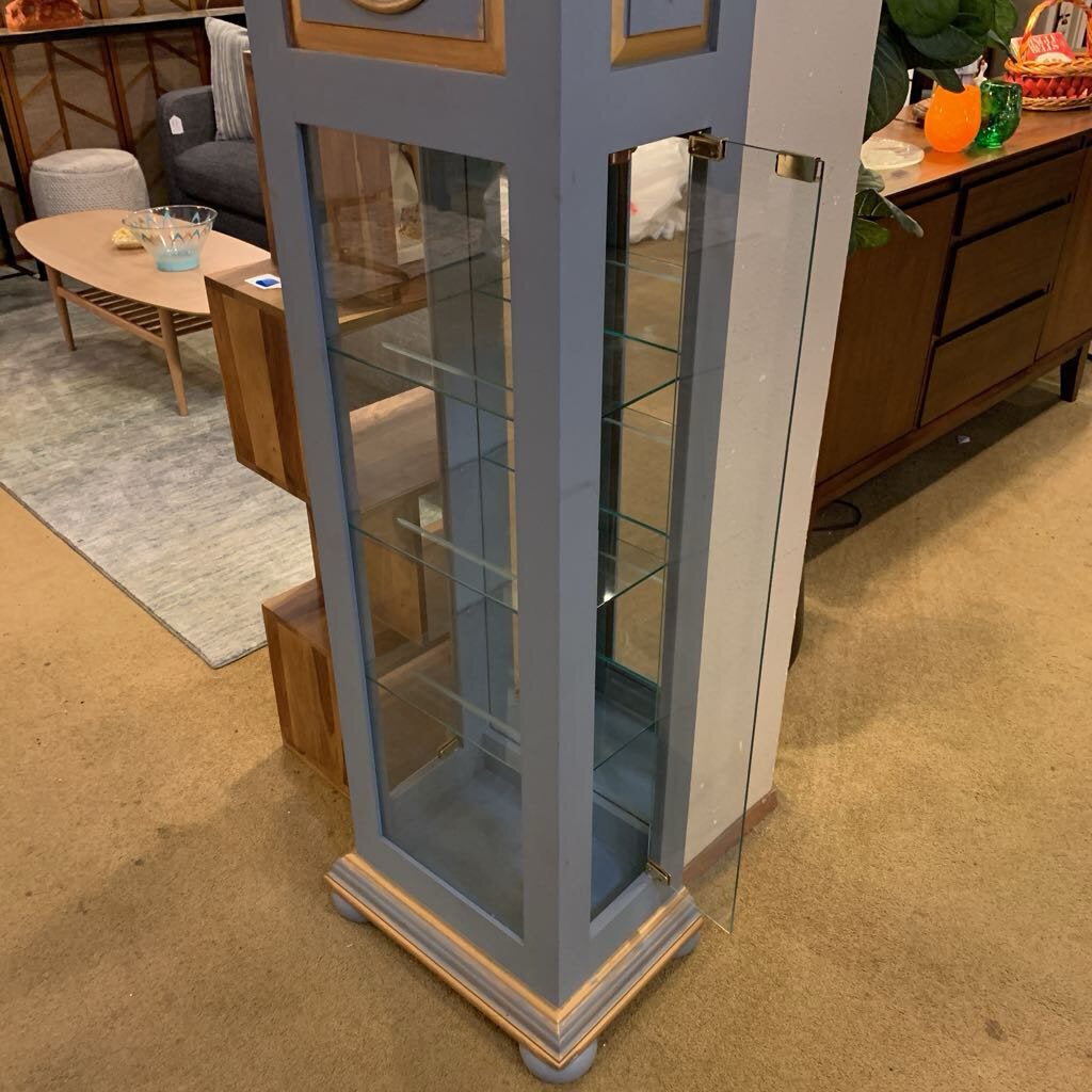 Tall glass display cabinet in a room with furniture and decor.