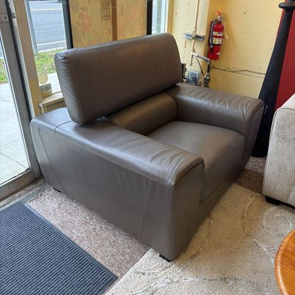 Gray leather armchair in a room with a fire extinguisher on the wall.
