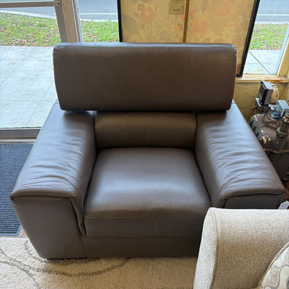 Brown leather armchair in a room with a window and door.