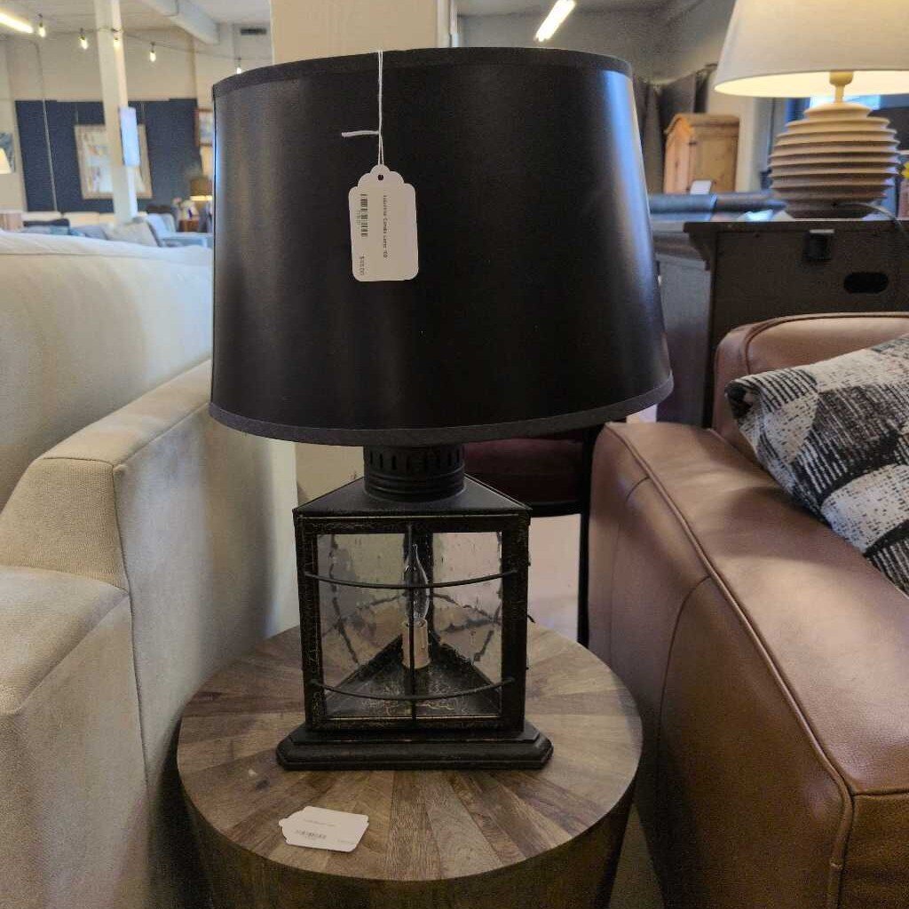 Black lamp with a tag on a wooden table in a room with furniture