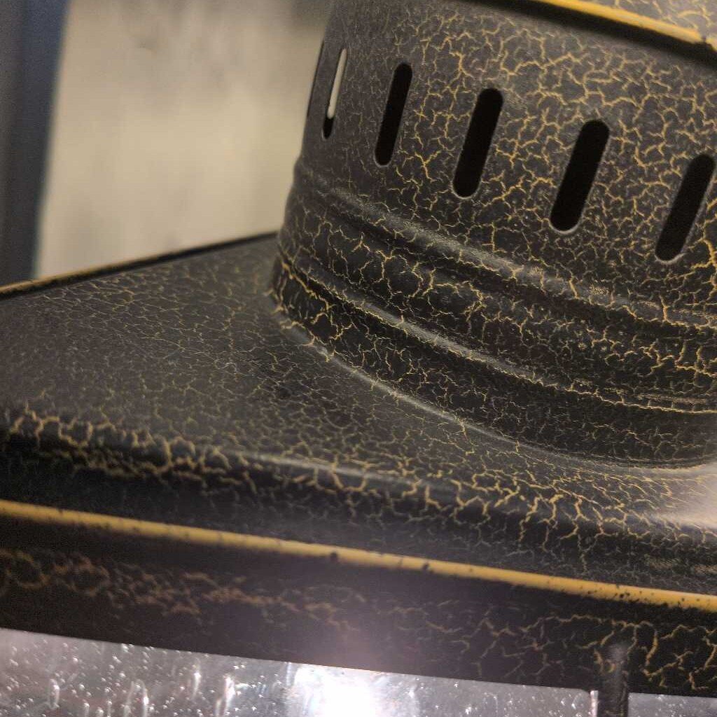 Close-up of a textured black object with circular cutouts on a reflective surface.