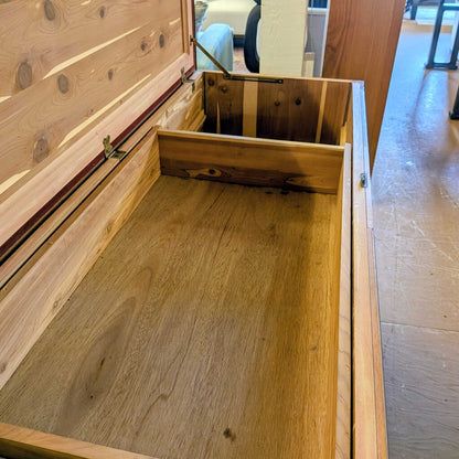 Wooden drawer or storage compartment with a visible wooden floor inside, set against an indoor background.