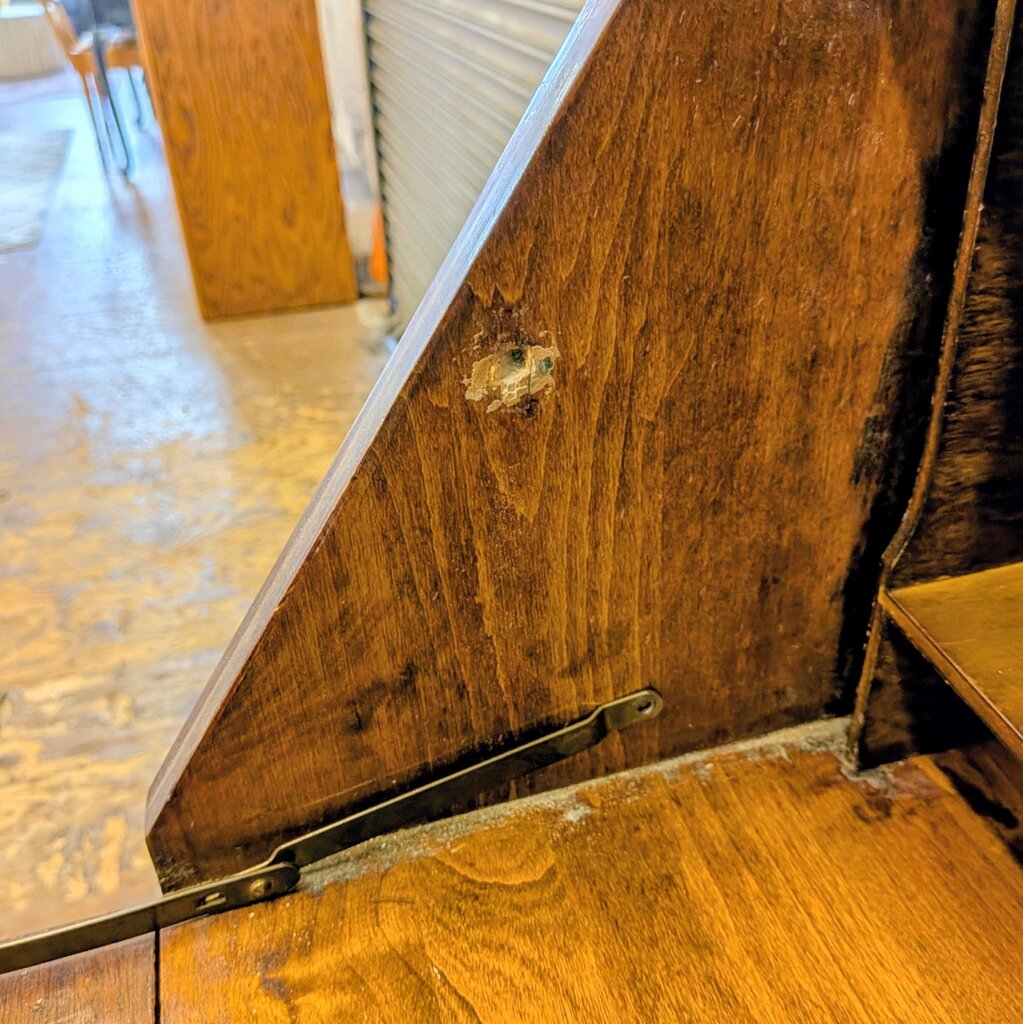Close-up of a wooden surface with a metal handle and visible wear.
