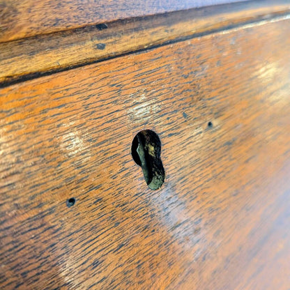 Close-up of a wooden surface with a small hole and dark object inside