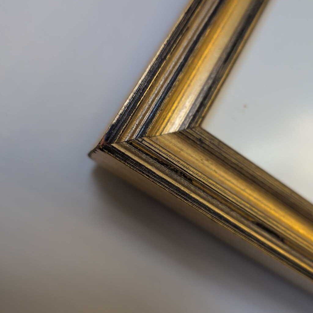 Close-up of a gold picture frame corner on a white background