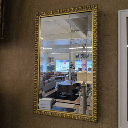 Gold-framed mirror on a textured wall reflecting a living room.