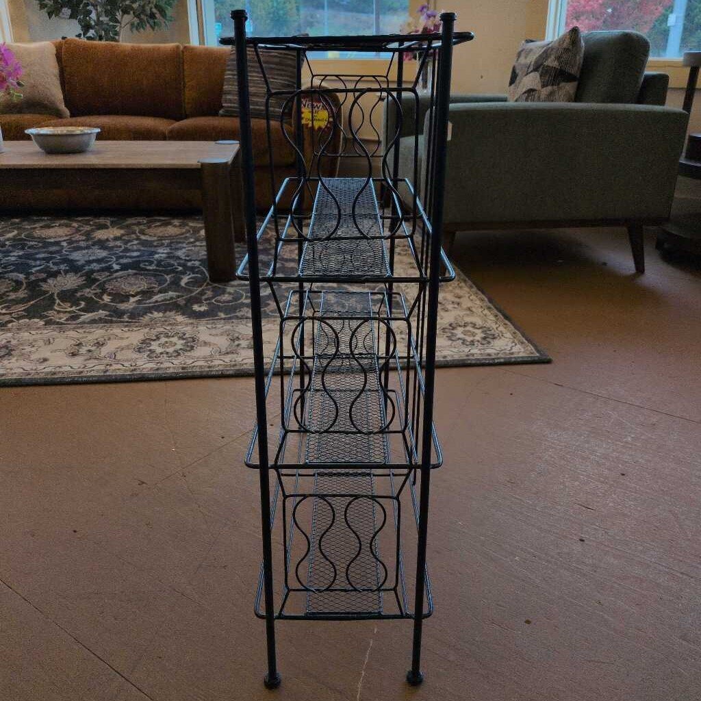 Black metal tiered shelf in a living room setting with furniture and decor.