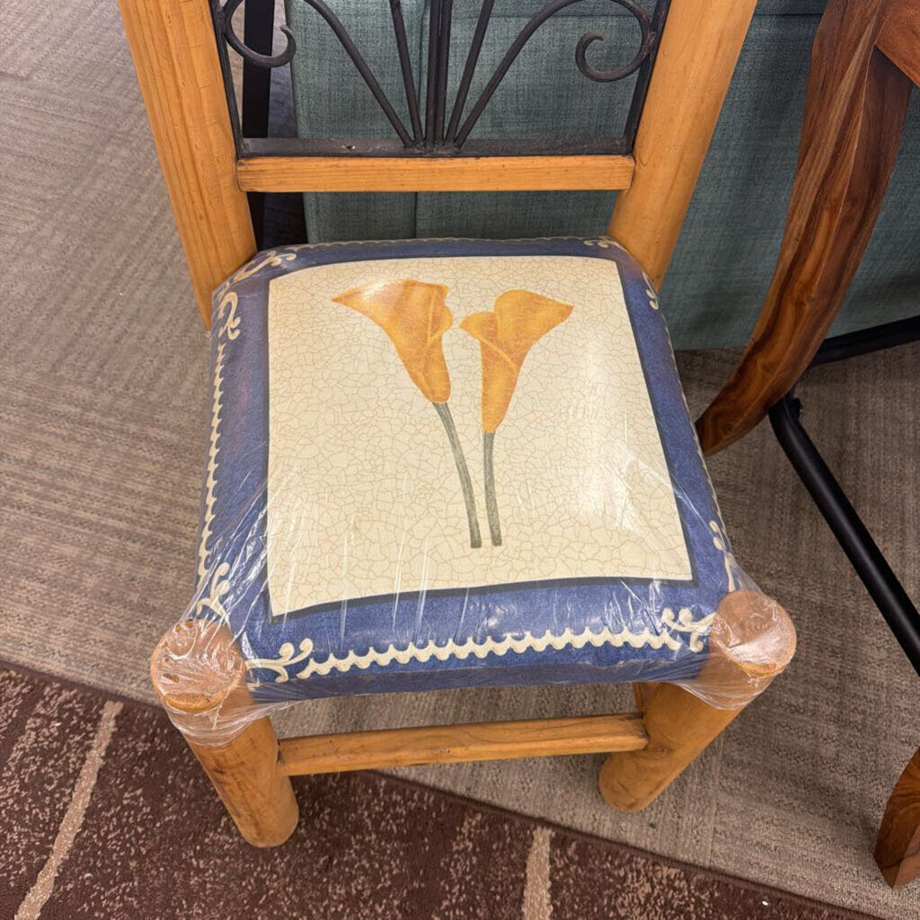 Chair with a decorative cushion featuring floral design on a carpeted floor.