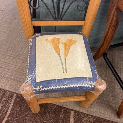 Chair with a decorative cushion featuring floral design on a carpeted floor.