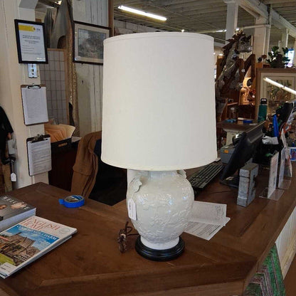 White textured lamp with a beige lampshade on a wooden desk in an office setting.