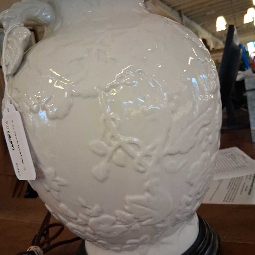 White textured vase with decorative patterns on a wooden floor.