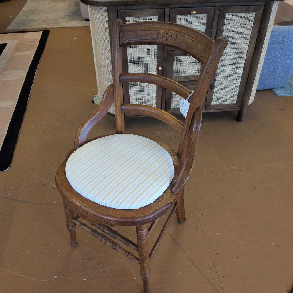 Wooden chair with a striped cushion on a brown floor