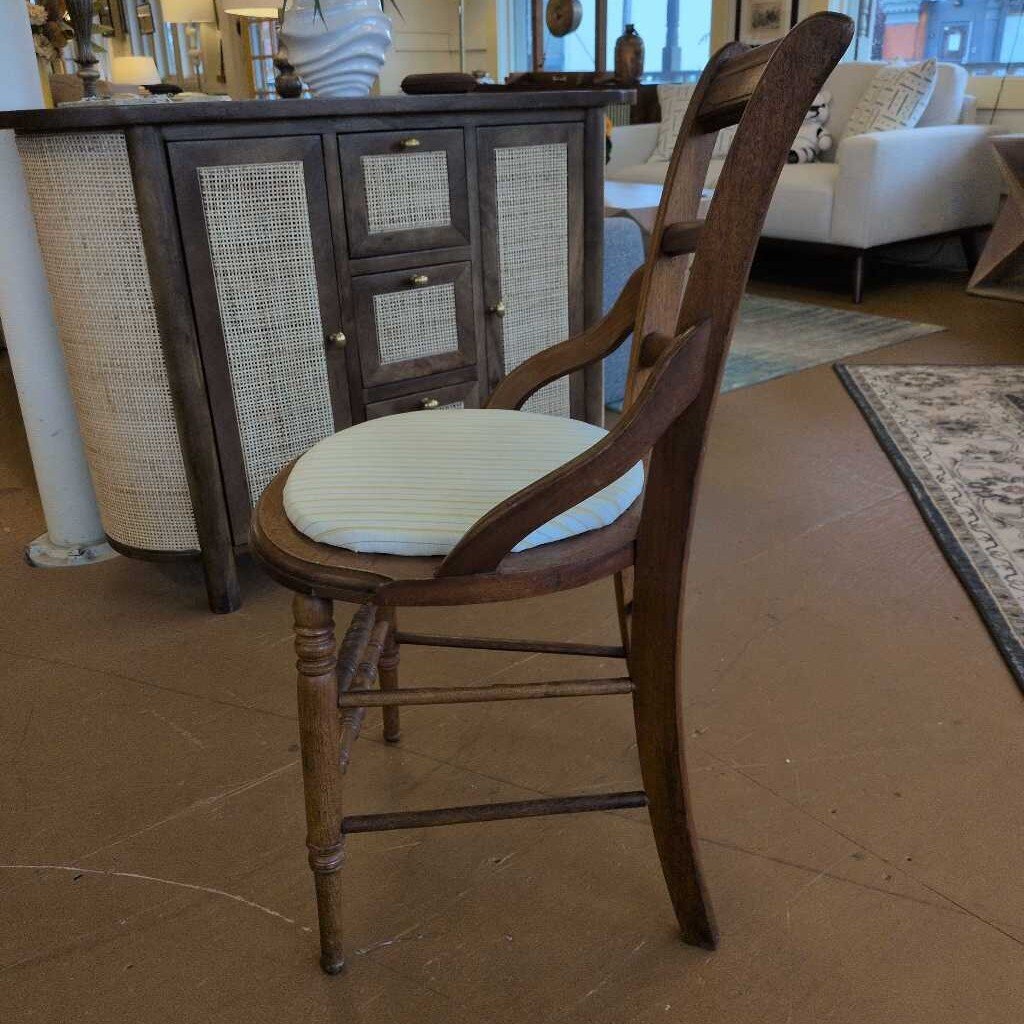 Wooden chair with a cushioned seat in a room with furniture and decor.