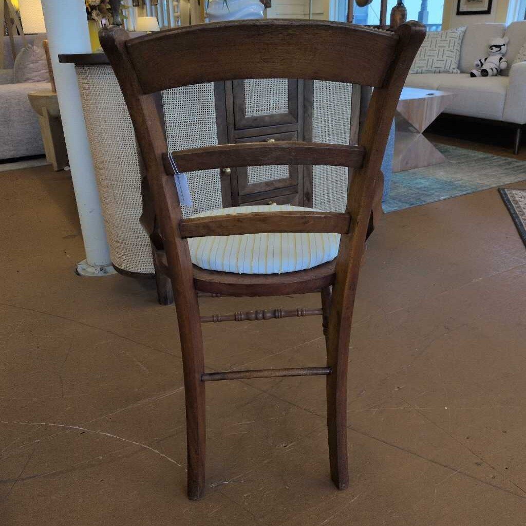 Wooden chair with a cushioned seat in a room with furniture and decor.